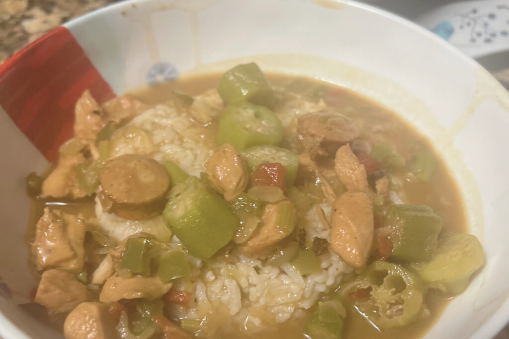 A steaming bowl of rich and flavorful gumbo, filled with a delightful mix of succulent shrimp, spicy andouille sausage, tender chicken, aromatic vegetables, and a savory blend of Creole spices, capturing the essence of Louisiana's culinary tradition